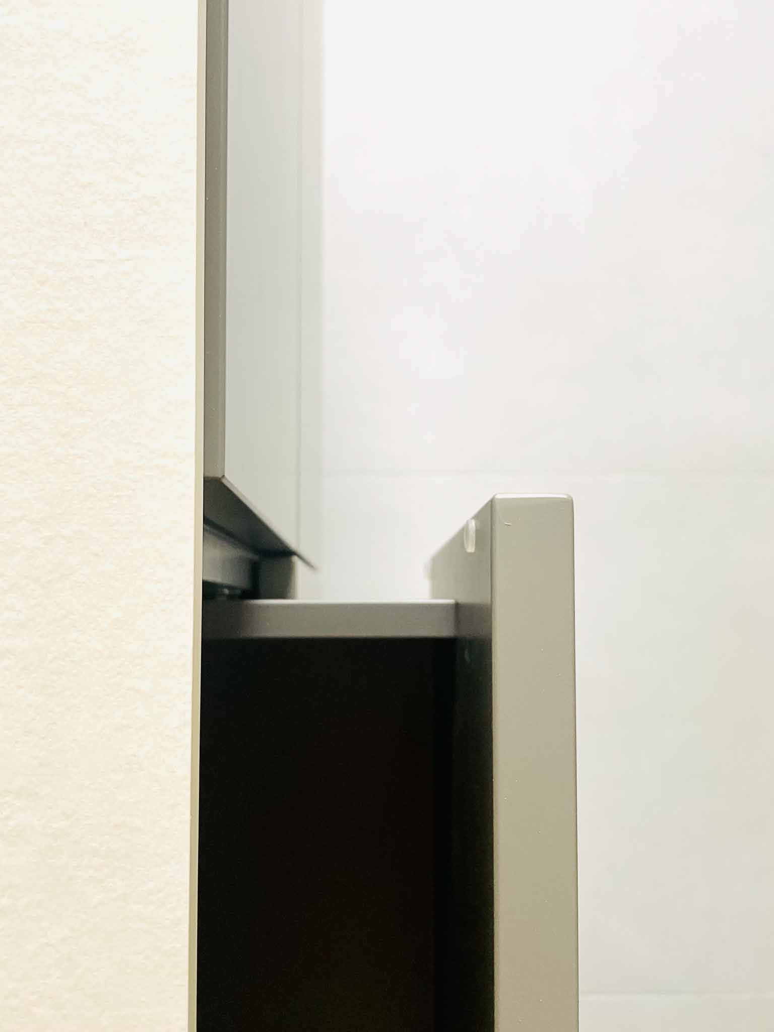 Offene graue Schrankschublade; dunkles Inneres. Hellgraue Zierleisten und weiße Wand.
