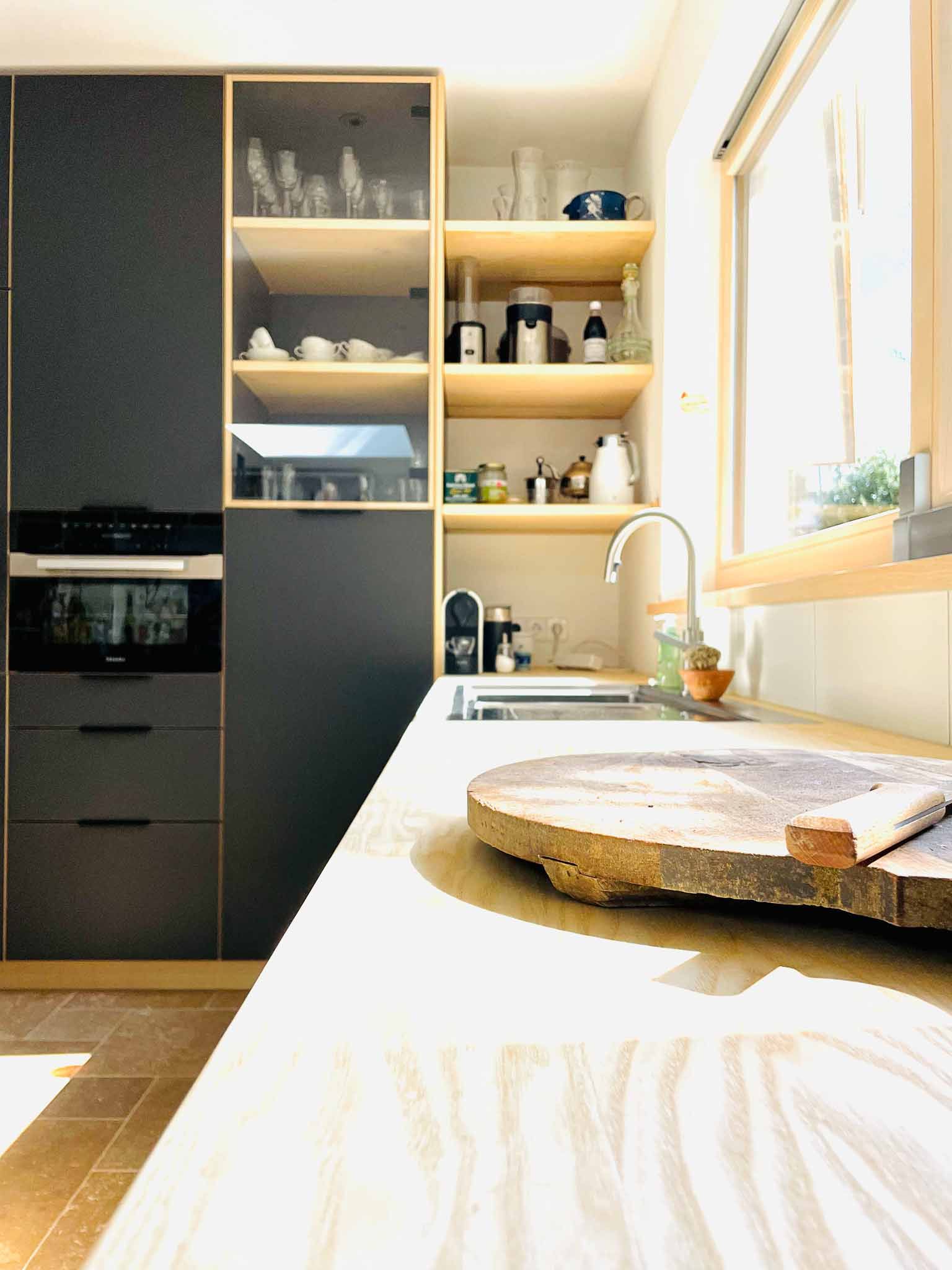 Küche mit dunkelgrauen Schränken, hellen Holzregalen und einer Holzarbeitsplatte.