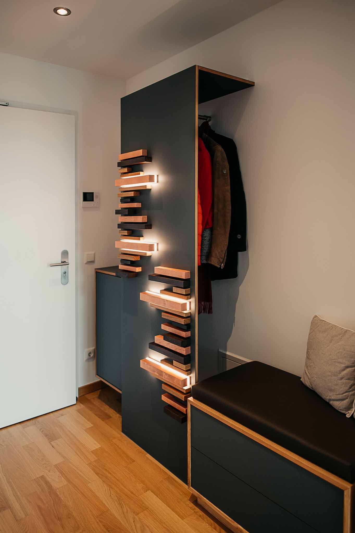 Moderner Flur mit blaugrünem und hölzernem Aufbewahrungsmöbel, Bank und Garderobe.