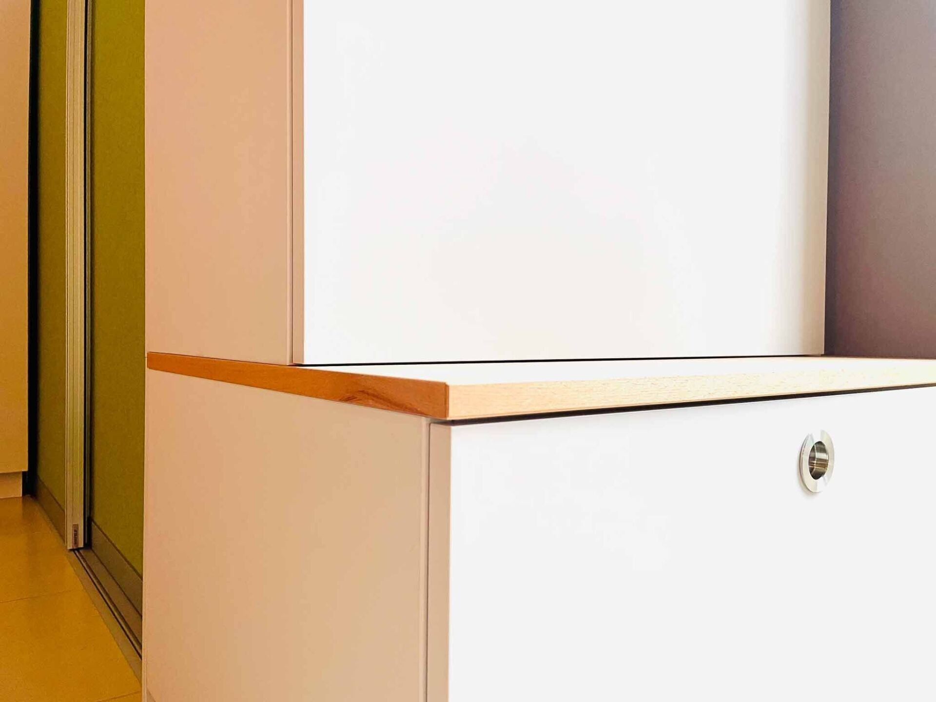 Weißer Schrank mit Holzplatte, Schloss und angrenzender limettengrüner Tür.