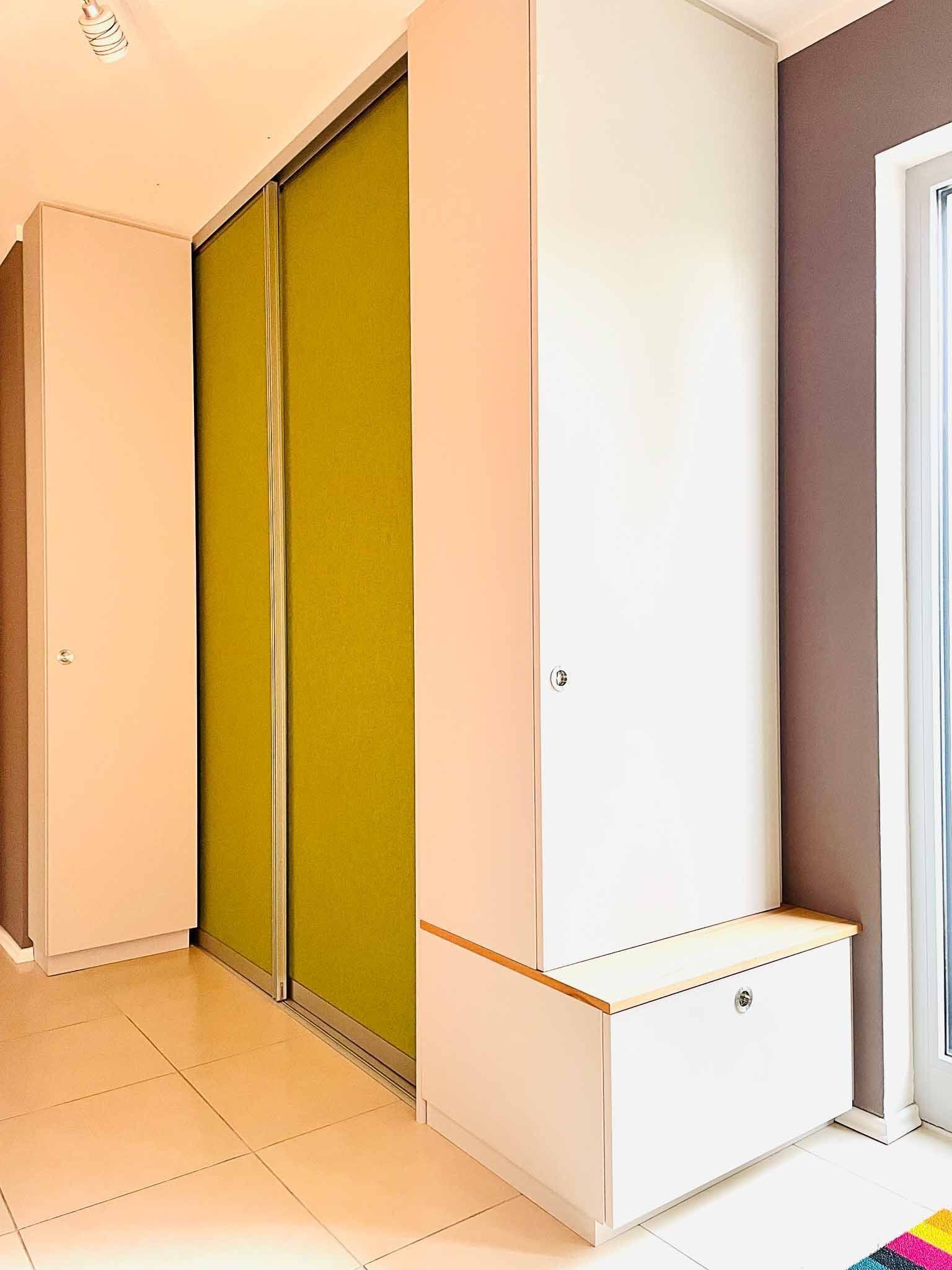 Weißer und limettengrüner Schrank mit einer weißen Aufbewahrungsbank in einem Flur.