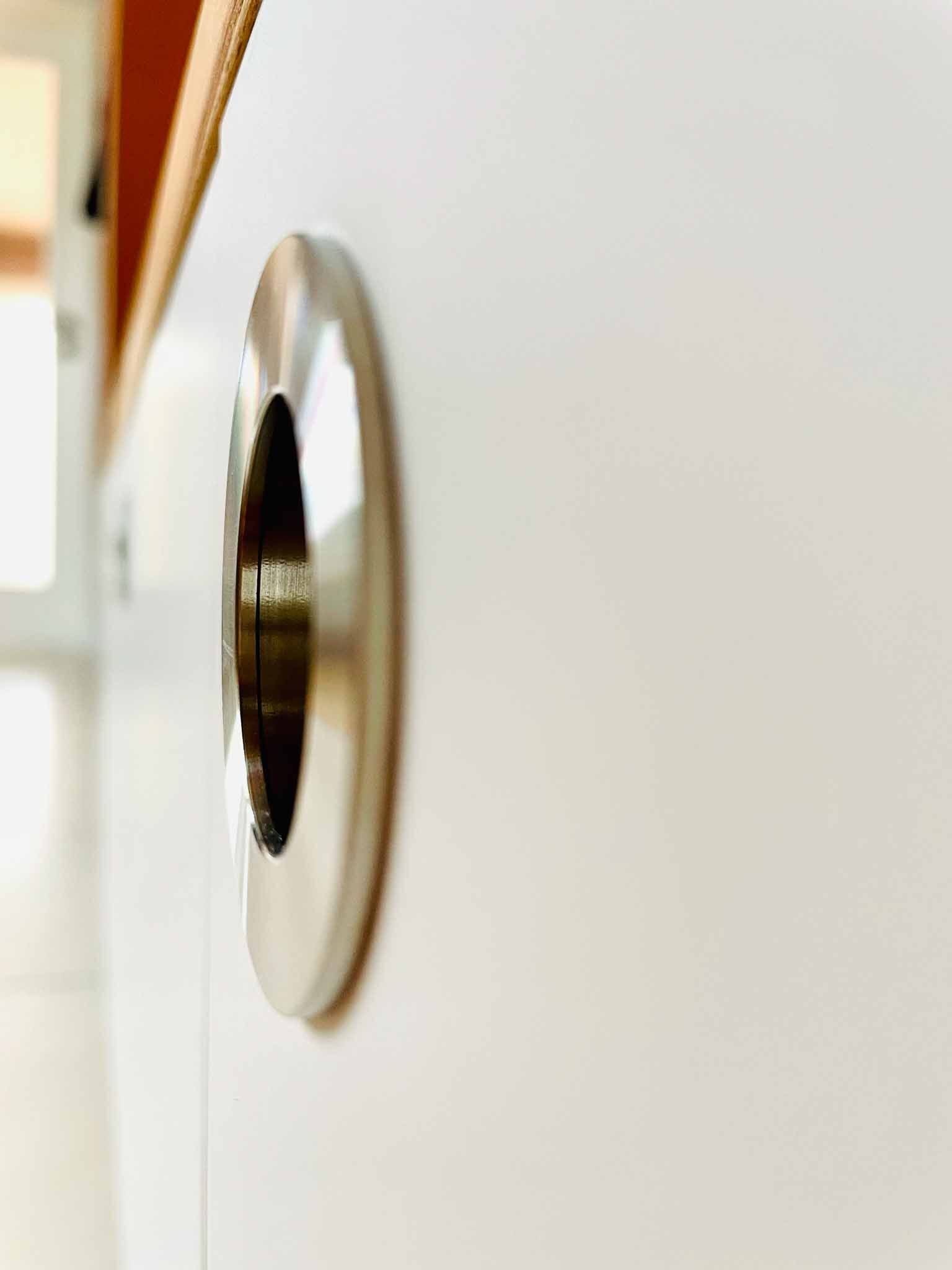 Glänzender Türgriff aus Metall auf einer weißen Oberfläche, Nahaufnahme.