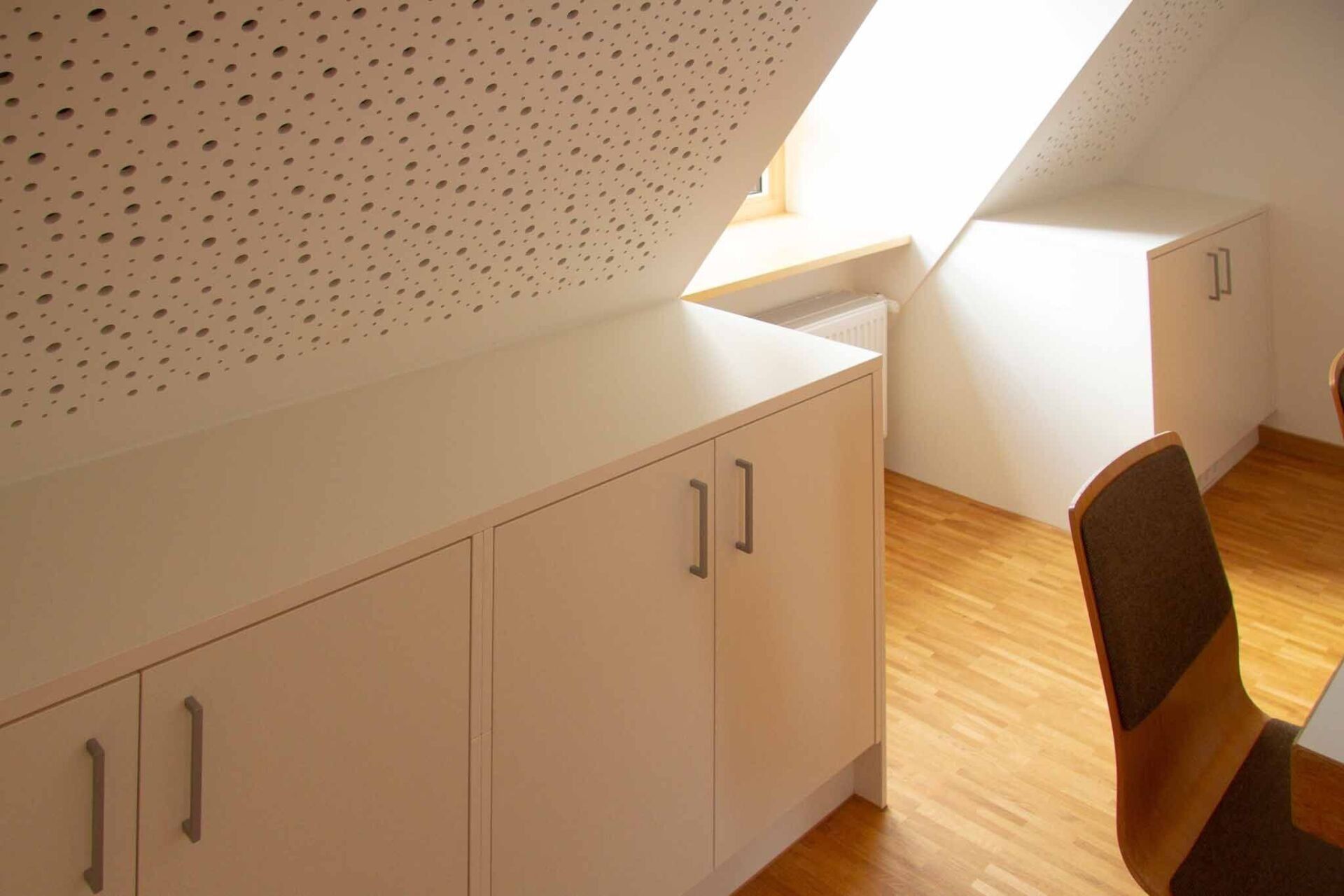 Weiße Schränke in einem Dachzimmer mit Dachschräge und Holzböden.