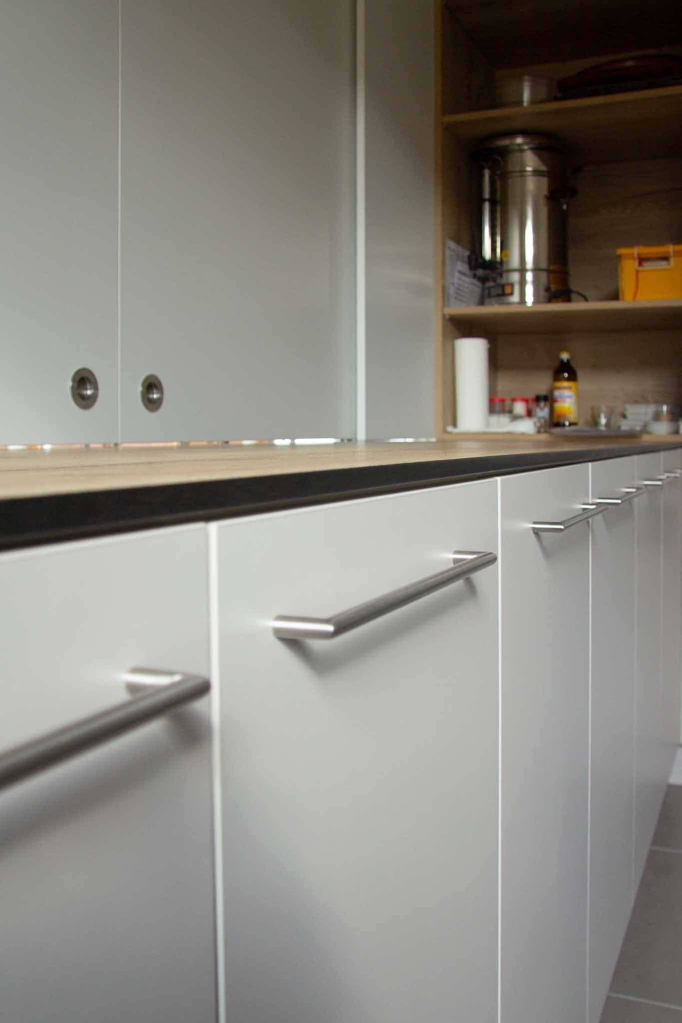 Weiße Küchenschränke mit silbernen Griffen.