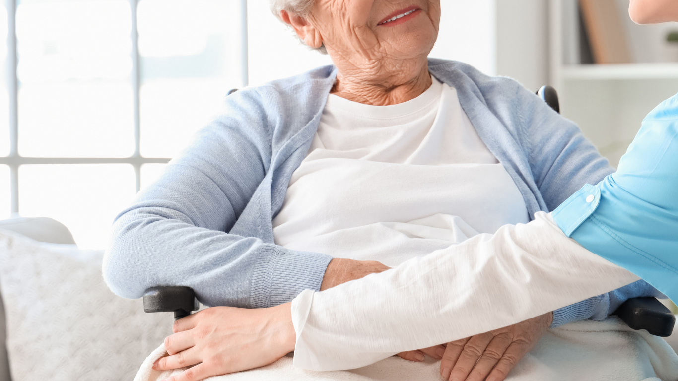 Hombre con gafas, sonriendo, metiendo la mano en un recipiente que está sobre el mostrador; otra persona observa en una cocina.