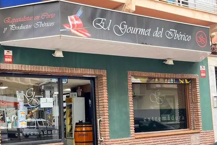 Sándwich relleno de carne y una copa de vino tinto sobre una superficie de madera.