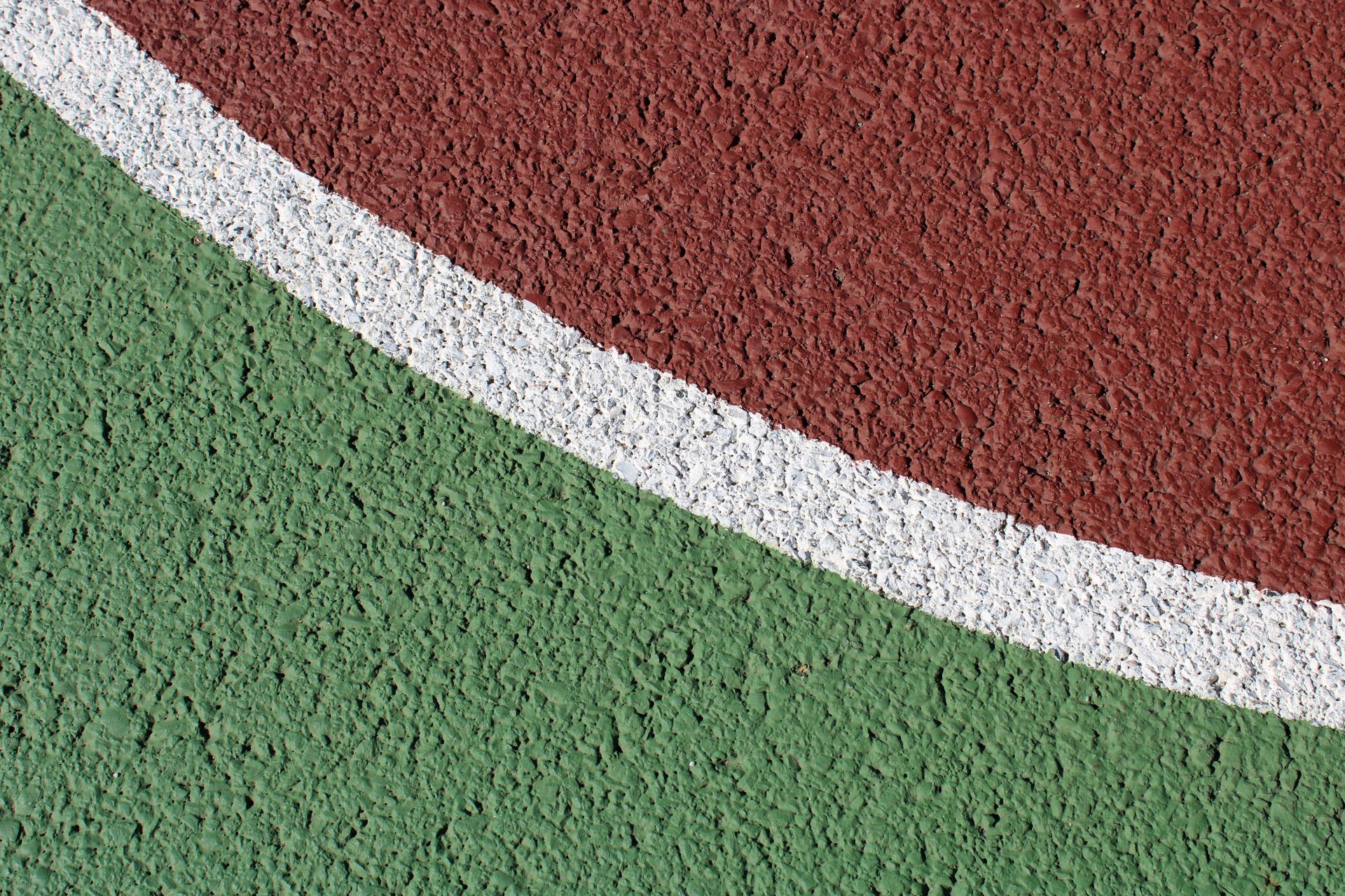 Surface texturée peinte en rouge et en vert, divisée par une ligne blanche courbe