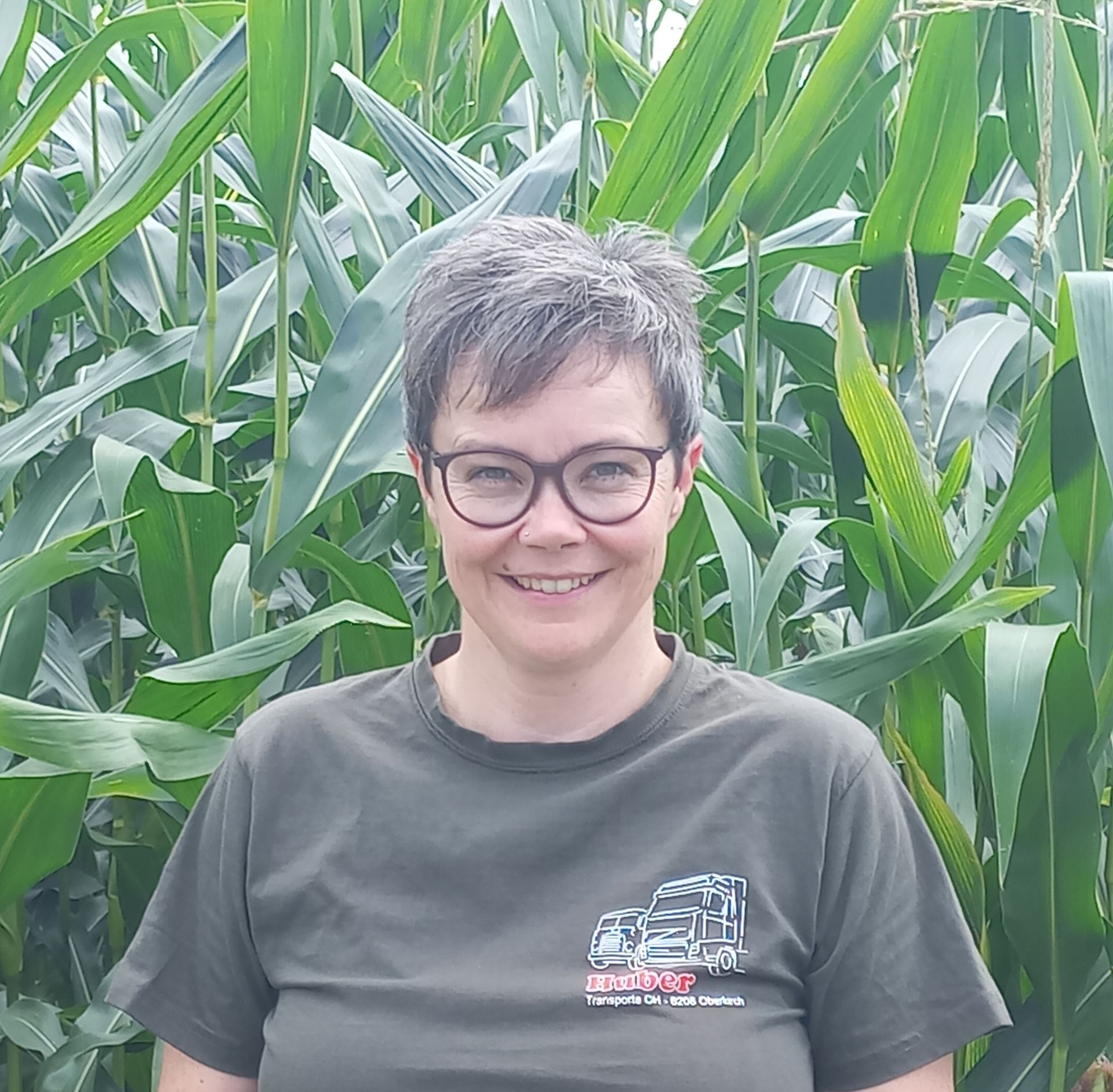 Eine Frau mit Brille und schwarzem Kapuzenpullover lächelt.