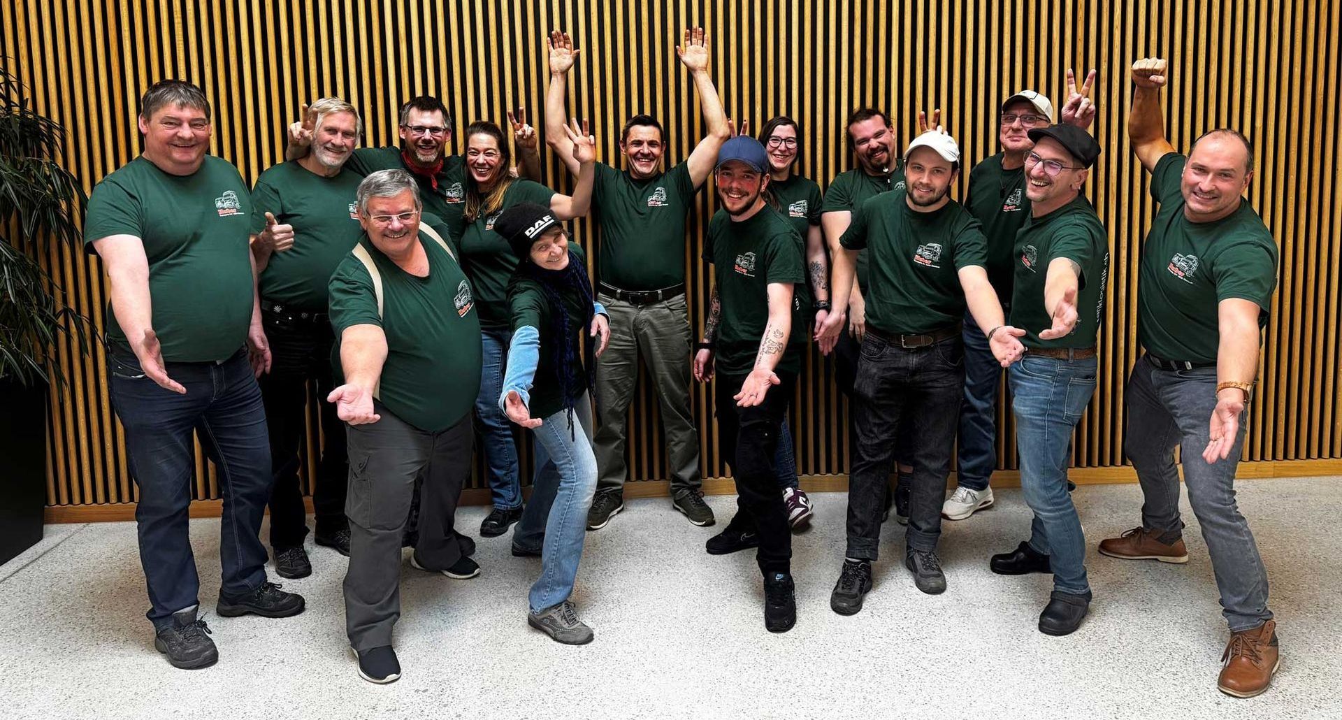 Eine Gruppe von Mitarbeiterin von K + R Huber Transporte GmbH in grünen T-Shirts posieren für ein Foto.