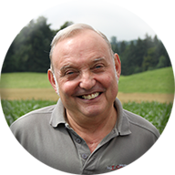 Ein Mann in einem grauen Hemd lächelt vor einem Feld