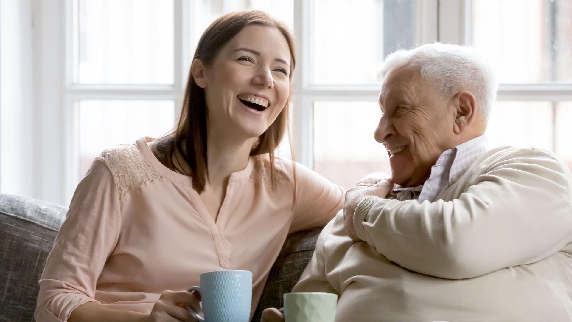 Jeune femme et grand-père souriant dans le canapé