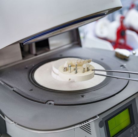 Molde dental siendo calentado en un dispositivo de laboratorio con pinzas que sujetan la muestra.