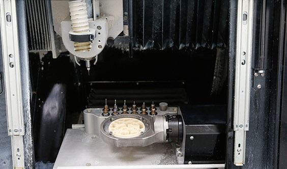 Interior de una máquina industrial con una pieza metálica central y paneles laterales negros.