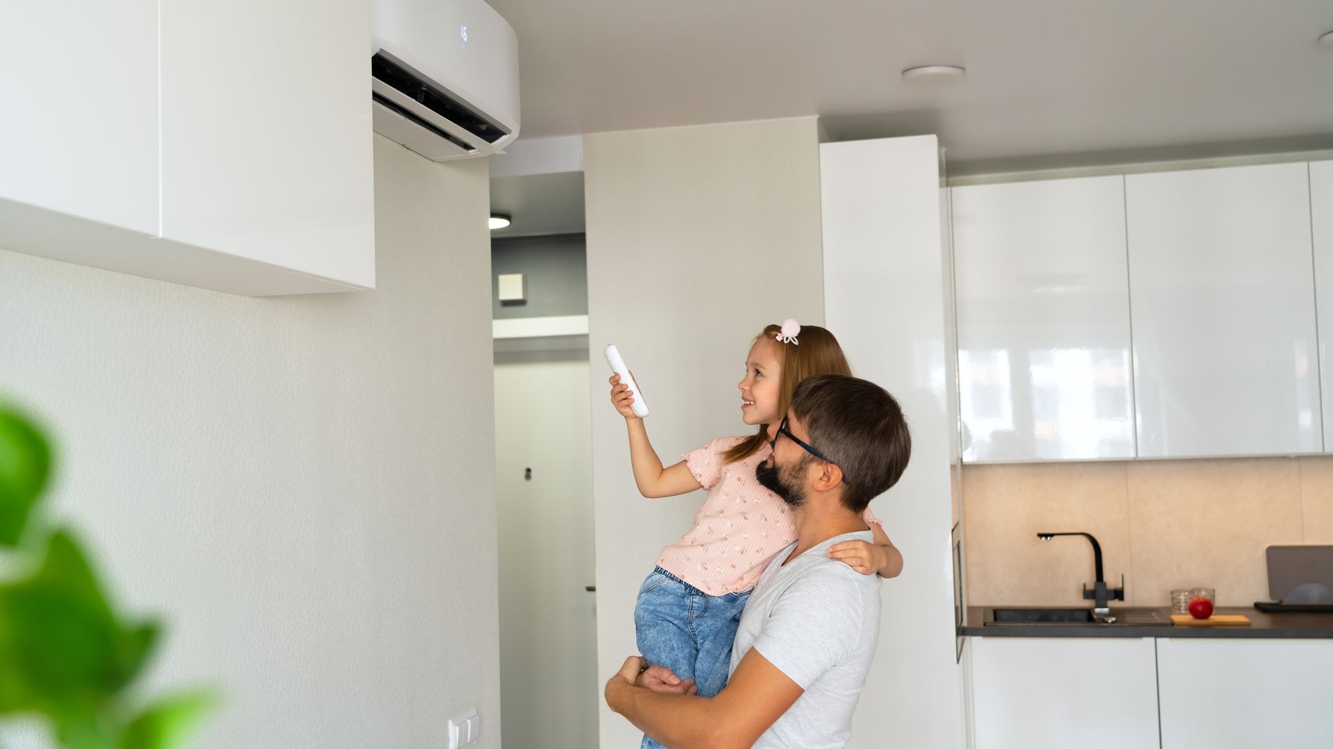 Un père et sa fille avec la télécommande d'un climatiseur