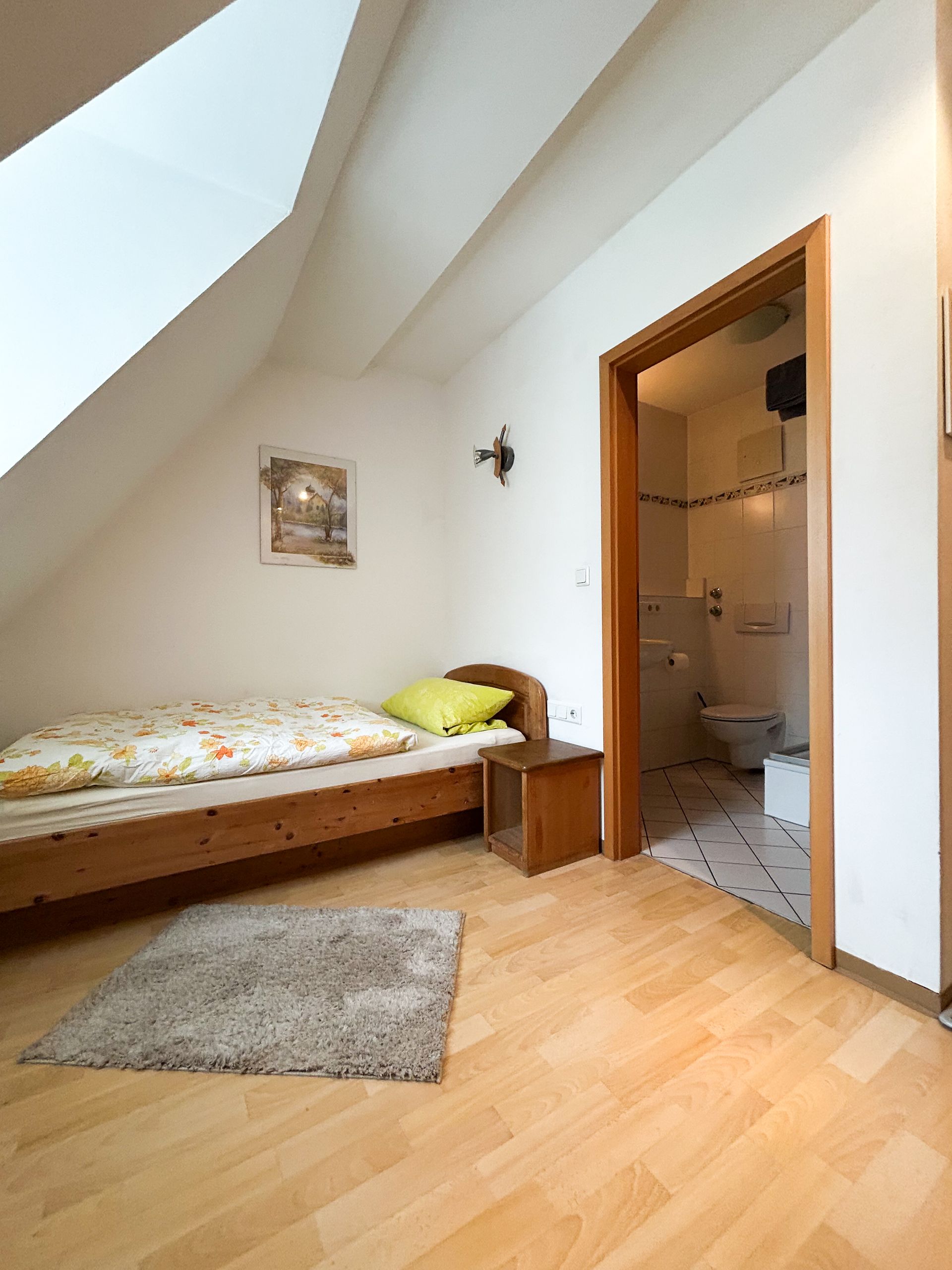 Frühstückstablett mit Kaffee, Saft, Croissants und Obst auf einem Tisch in einem Hotelzimmer.