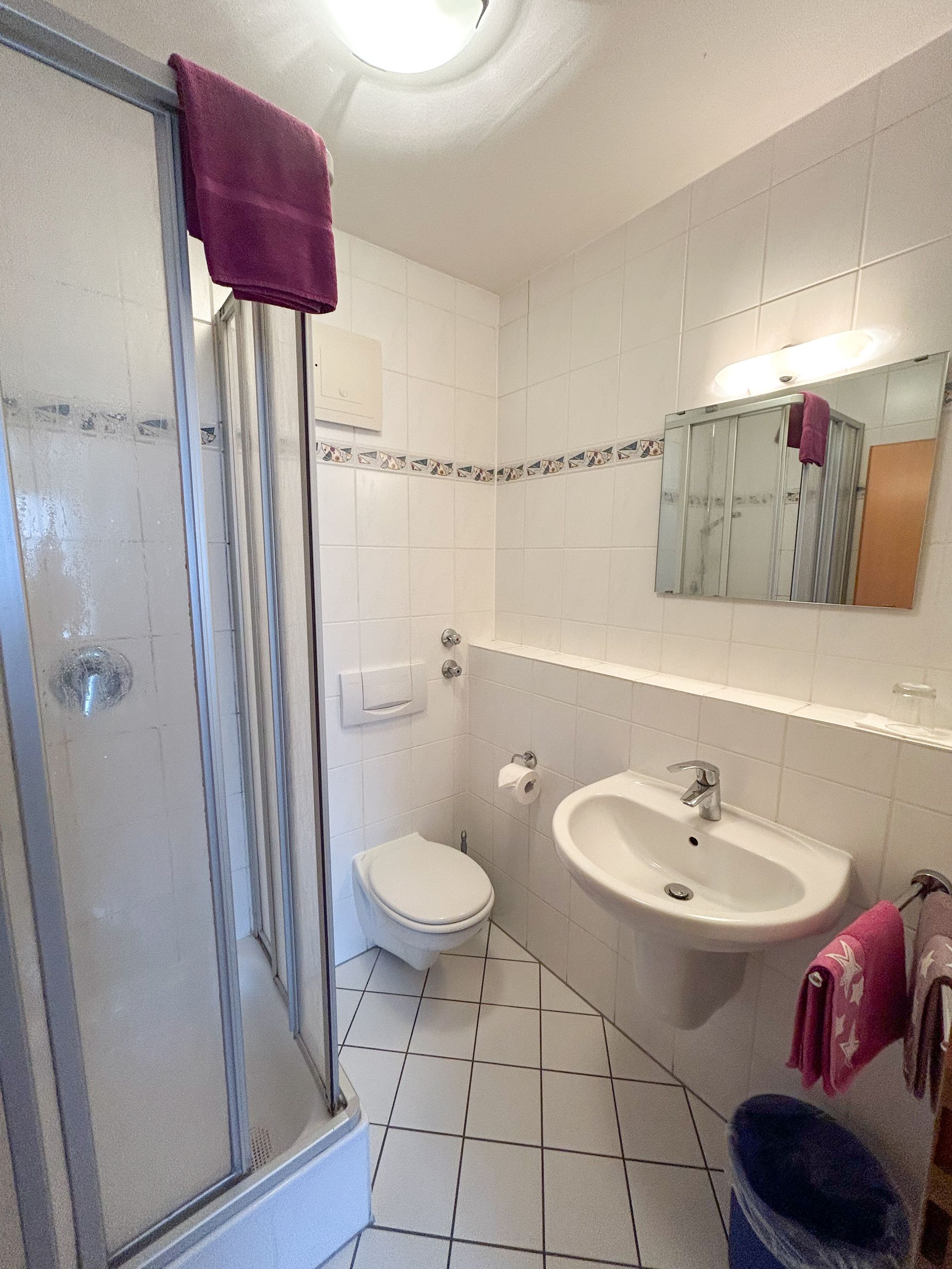 Frau öffnet mit einem Koffer Fensterläden in einem hellen Wohnzimmer.