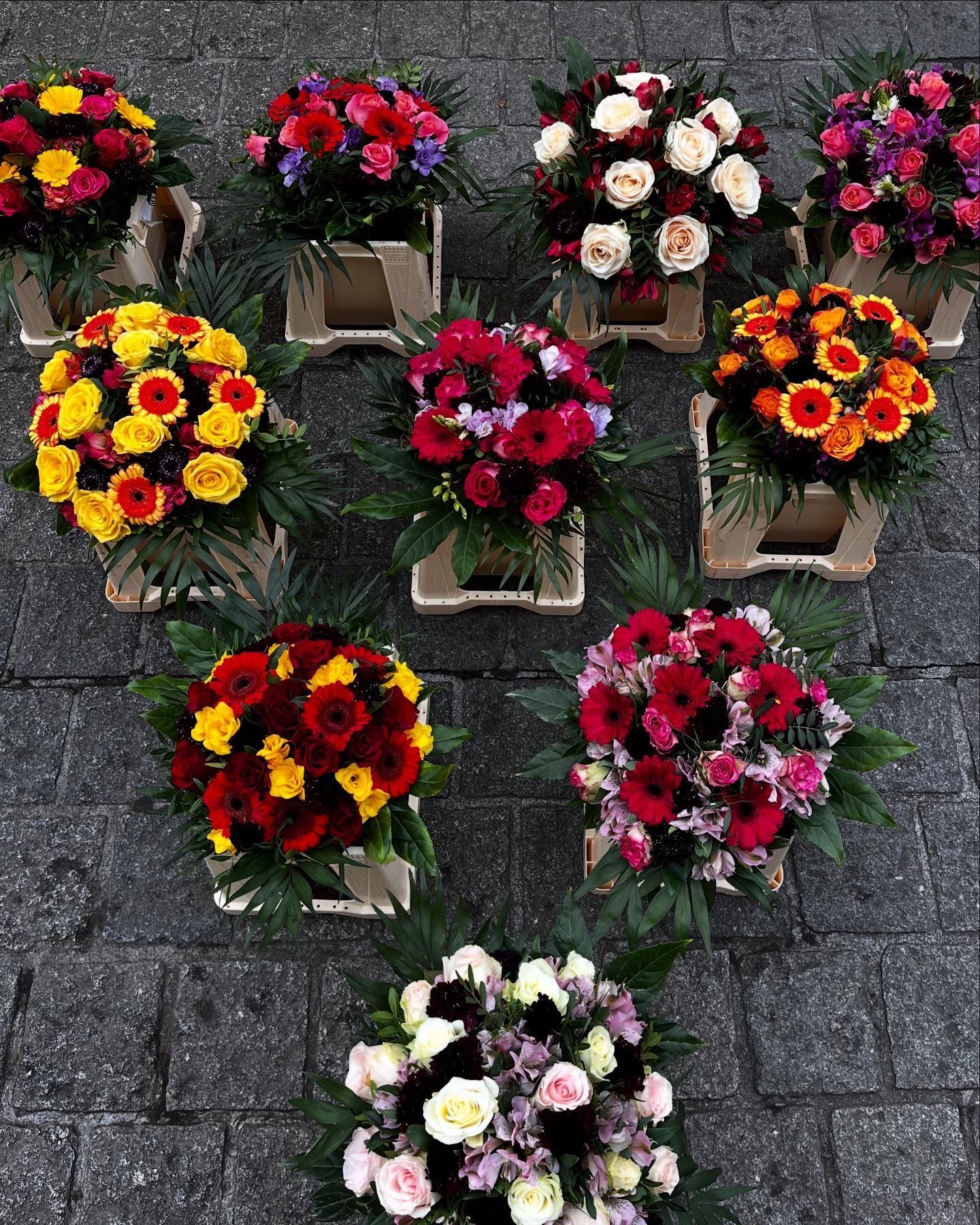 Anordnung bunter Blumensträuße auf Kopfsteinpflaster.
