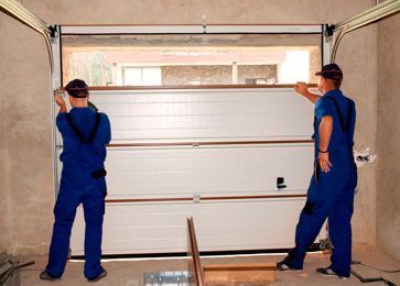 Dos hombres están instalando una puerta de garaje en un garaje.