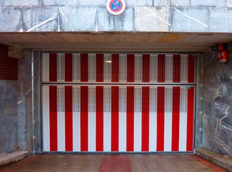 Una puerta de garaje con rayas rojas y blancas está abierta en un estacionamiento.