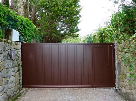 Una puerta corrediza marrón se abre a un camino de entrada.