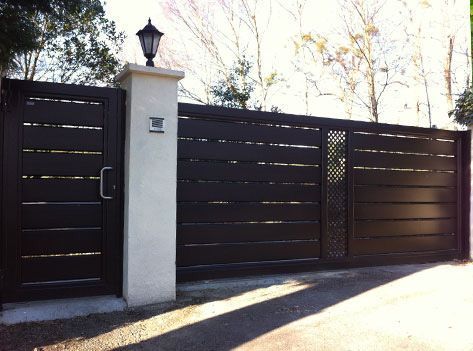 Una puerta negra con una lámpara encima.