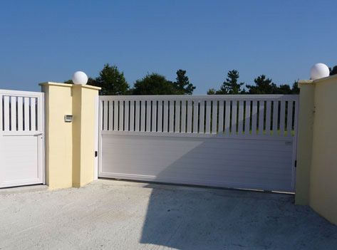 Una puerta corrediza blanca se abre a un camino de entrada.