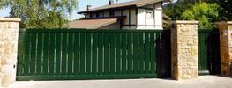 Una puerta corrediza verde está abierta delante de una casa.