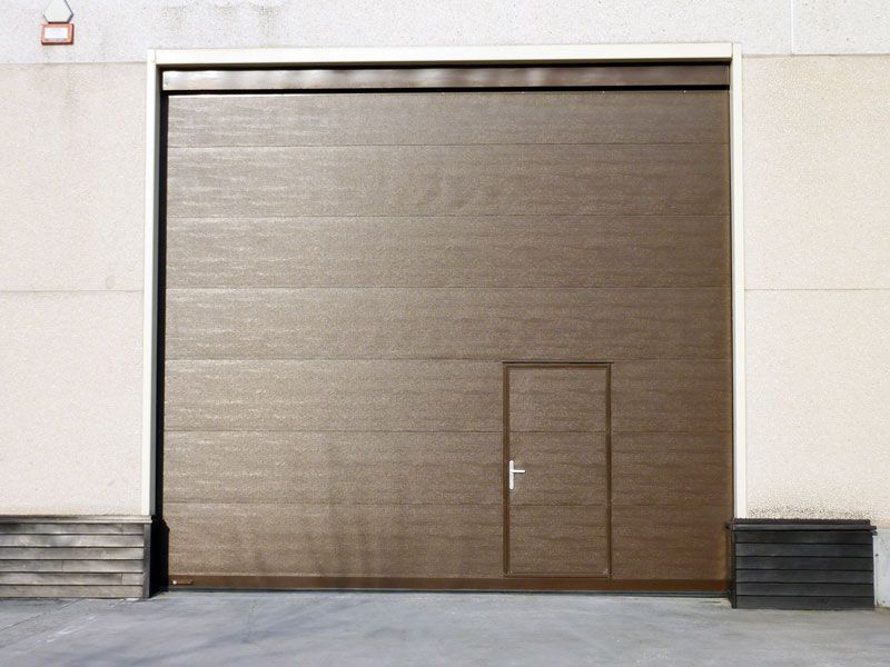 Una puerta de garaje marrón con una pequeña puerta debajo.