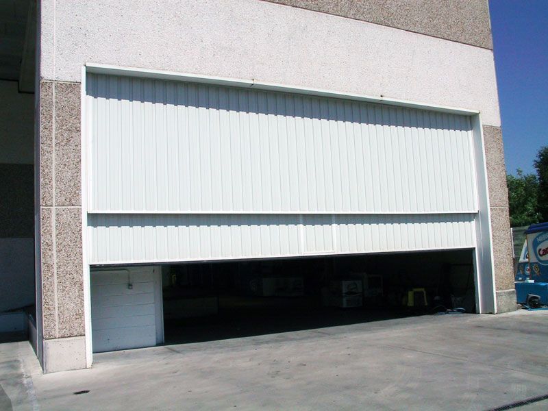 Una gran puerta de garaje blanca está abierta frente a un edificio.