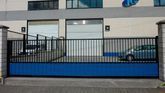 Una valla azul rodea un edificio con un coche aparcado delante.