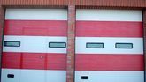 Un par de puertas de garaje rojas y blancas en un edificio de ladrillo.