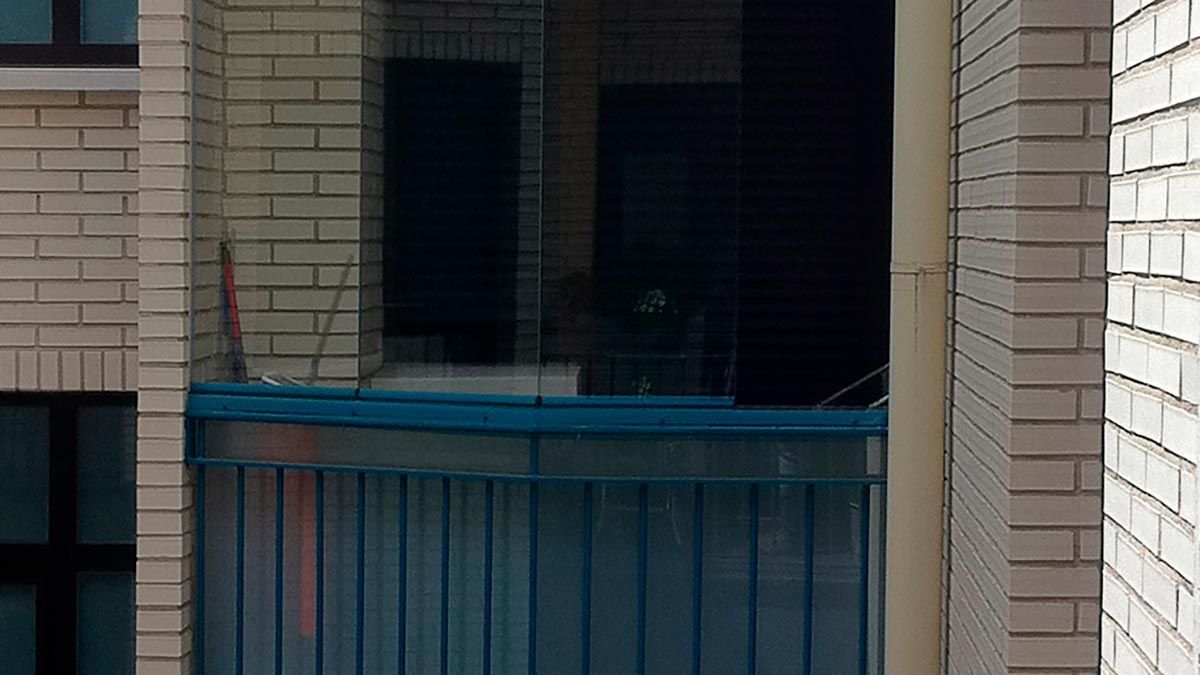 Un balcón con barandilla azul está entre dos edificios de ladrillo.