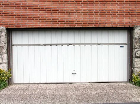 Una puerta de garaje blanca está abierta frente a un edificio de ladrillo.