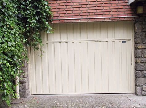 Una puerta de garaje blanca con una pared de ladrillos detrás.