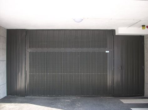 Una gran puerta de garaje negra está abierta en un estacionamiento.
