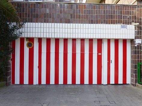 Una puerta de garaje a rayas rojas y blancas con una señal de no estacionar