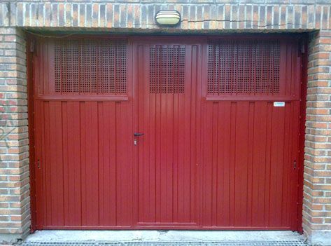 Una puerta de garaje roja está contra una pared de ladrillos.