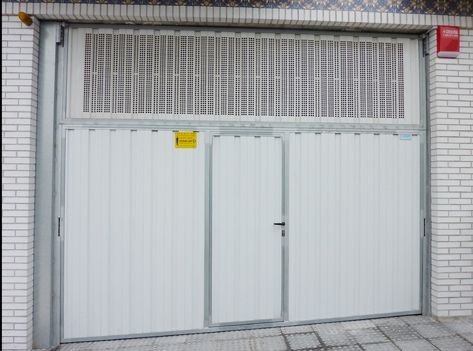 Una puerta de garaje blanca con una pared de ladrillos detrás.