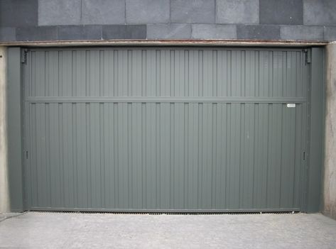 Una puerta de garaje gris está abierta a un camino de entrada.