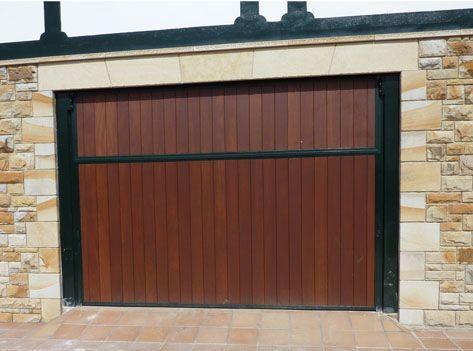 Una puerta de garaje de madera frente a un muro de piedra