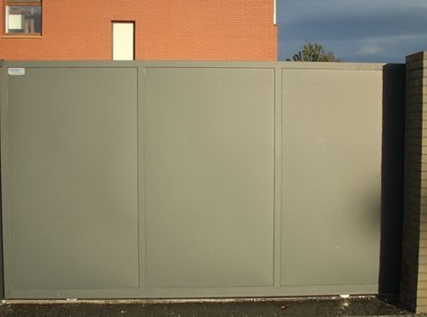 Una puerta corrediza gris frente a un edificio de ladrillo.