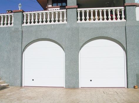 Dos puertas de garaje blancas arqueadas en el costado de un edificio