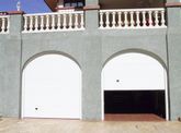 Una puerta de garaje está abierta delante de una casa con balcón.