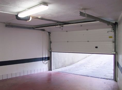 Un garaje con la puerta del garaje abierta y una luz en el techo.