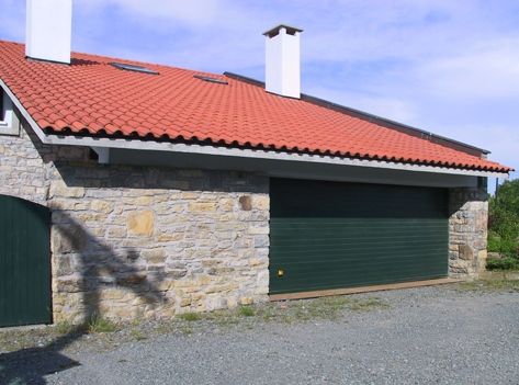 Una casa con una puerta de garaje verde y un techo de tejas rojas