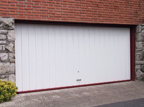 Una puerta de garaje blanca está abierta frente a un edificio de ladrillo.
