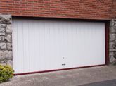 Una puerta de garaje blanca está situada en el costado de un edificio de ladrillos.