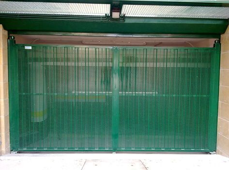 Una puerta verde está abierta en un garaje con una pared de ladrillos detrás de ella.