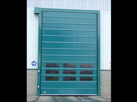 Una puerta de garaje verde está situada al costado de un edificio.