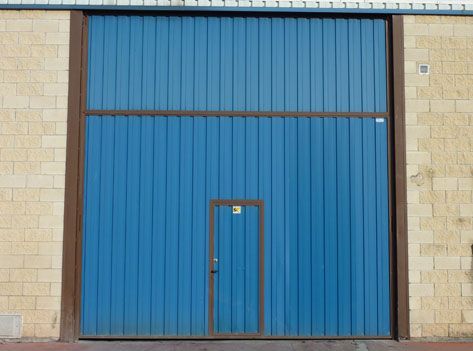 Una puerta de garaje azul con una pequeña puerta en el medio.